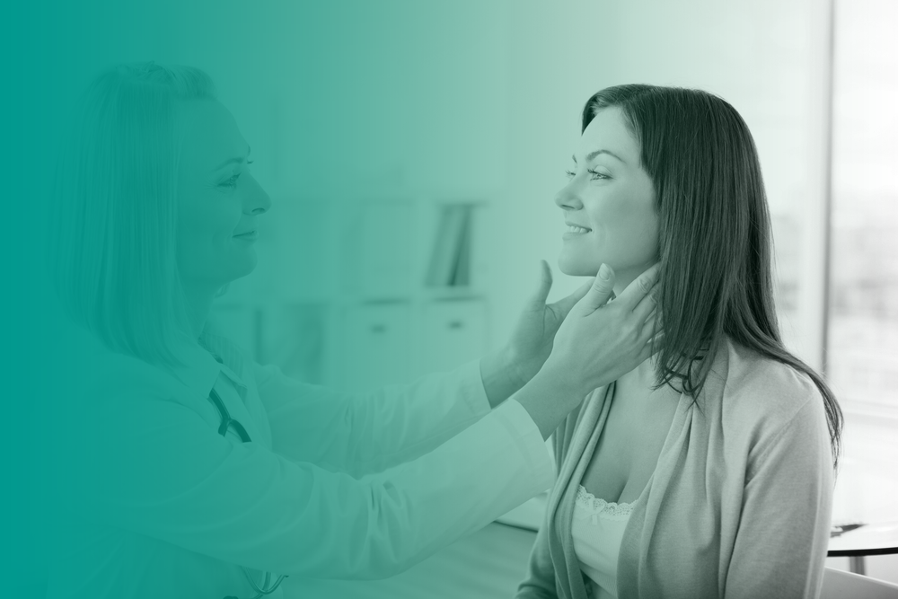 A woman smiles as she receives a medical check up from a friendly-looking female nurse practitioner.