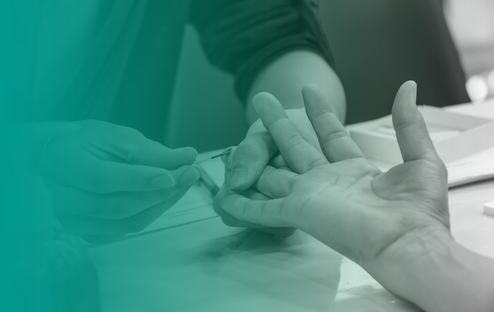A close up of a medical practitioner doing a finger prick test to perform a cholesterol check.