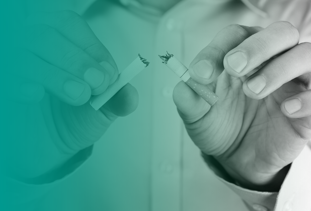 A close up of a person snapping a cigarette in half to signify that they have quit smoking.