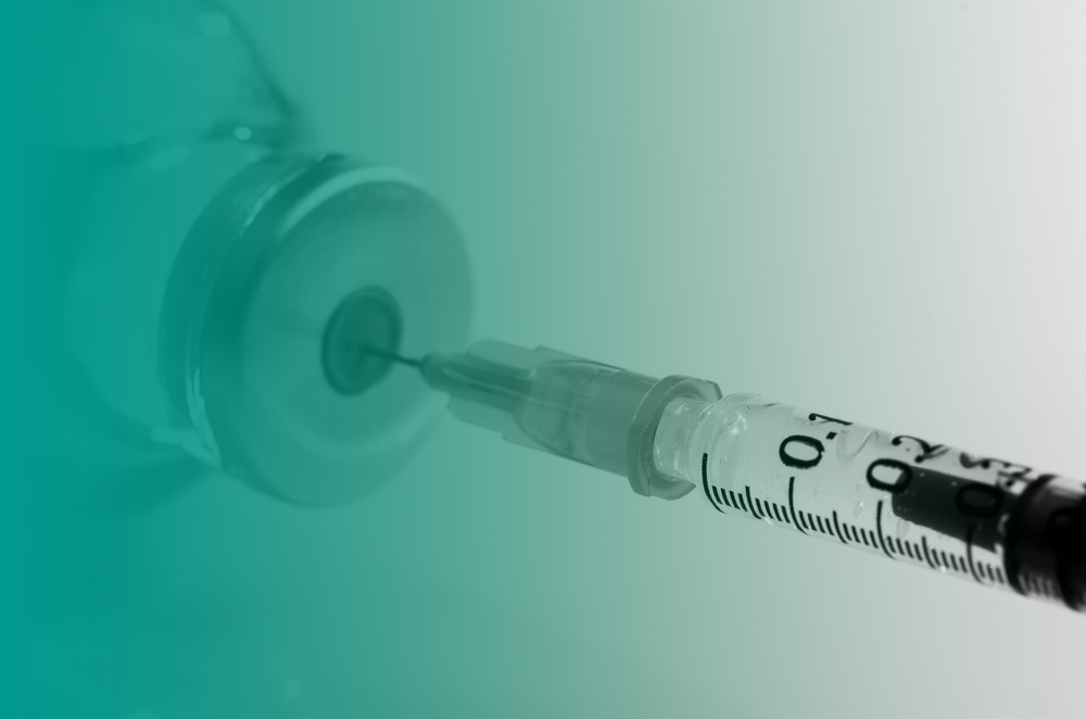 A syringe takes up a liquid vaccine to provide a vaccination.