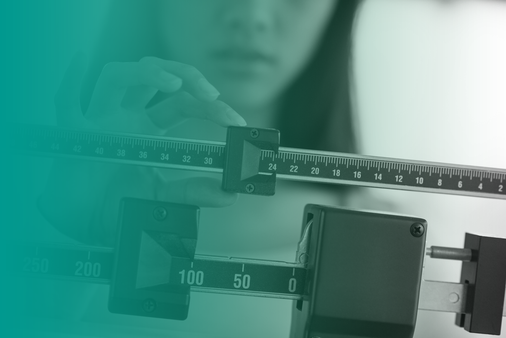 A woman adjusts weighing scales used as part of a weight management or weight loss program.